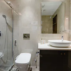 A sophisticated bathroom design that blends dark and light tones. The walk-in shower has a built-in seat, and the vanity provides ample storage. The space feels clean, organized, and luxurious.