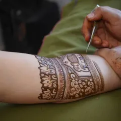 A close-up of my hand at work, carefully drawing a design on a client's arm. Every line is drawn with precision and care.
