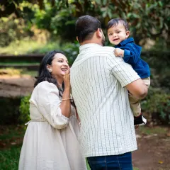 A candid, over-the-shoulder shot of a baby boy smiling at his mom. These unposed, natural moments during an outdoor family shoot are often the most cherished.