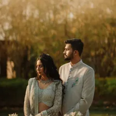A serene portrait of the couple amidst white flowers and soft, golden light. Their calm expressions and coordinated outfits give this image a peaceful and sophisticated quality.