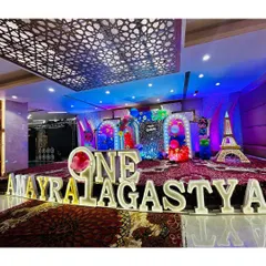 A wide shot of the Cocomelon stage for 'AMAYRA & AGASTYA', showcasing the full setup with multiple themed backdrops and props.
