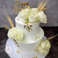 This elegant two-tier cake in pure white is adorned with fresh white roses, delicate wheat stalks, and gold leaf accents. It’s a timeless design perfect for a sophisticated 45th birthday celebration.