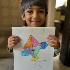 A young boy smiles with his colourful kite drawing for Makar Sankranti. We celebrate this festival by creating art that is full of movement and joy.