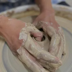 A classic shot of 'opening the clay' on the wheel. This is the foundational step where you create the initial space that will become the inside of your bowl or cup.