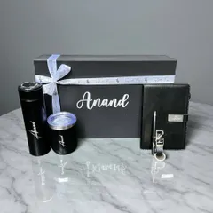 A sleek and modern Rakhi gift set for a brother named Anand. This all-black hamper includes a personalized box, an engraved flask and tumbler, and a matching diary set.