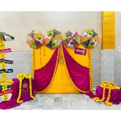 A creative Haldi setup featuring a bright yellow and magenta backdrop decorated with Rajasthani umbrellas and marigold garlands. The custom directional signs add a fun, personalized touch to the event.