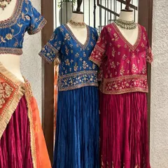 A closer look at the royal blue and fuchsia pink lehenga sets, showcasing the intricate gold floral embroidery on the blouses.