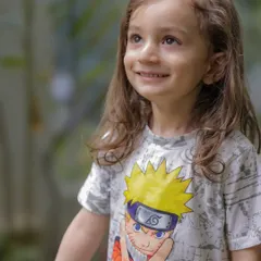 A sweet, upward glance from a little girl in her Naruto t-shirt. This natural portrait, taken outdoors, showcases her innocent curiosity and beautiful features.