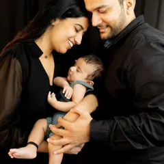 A complete family, held together by love. This classic portrait pose with a dark background creates a timeless, intimate feel that focuses entirely on your new family's connection.