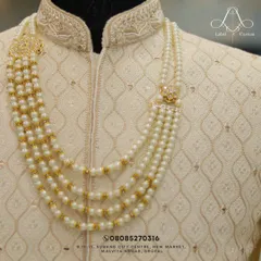 Another look at the fine details. The layered pearl necklace with gold accents sits perfectly on the textured fabric of this custom sherwani.
