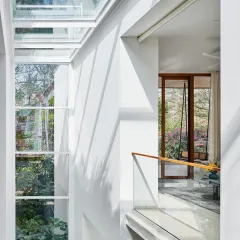 Looking across the connecting bridge in the Split House, you can see how the large skylight floods the multi-level space with natural light. This design element is key to the home's open and airy feel.
