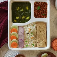 This is one of my favorite veg thalis, packed in a biodegradable tray. It comes with creamy Palak Paneer, hearty Rajma, fragrant Peas Kaju Rice, two chapatis, and a fresh salad.