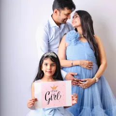 A beautiful maternity and family shoot announcing "It's a Girl." The older sister proudly holds the sign, sharing in the excitement of the growing family.