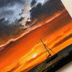 A close up shot of my acrylic painting featuring a sailboat against a fiery orange sunset. The texture of the canvas and the brushstrokes on the dark clouds and vibrant sky are clearly visible.
