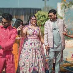 The color of happiness. Prachi and Vivek make their entrance, holding hands and smiling, perfectly embodying the joyful spirit of their Rajasthani wedding celebration.