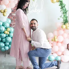 This is a sweet, candid moment between the parents-to-be at their baby shower. The colorful balloon decor adds a festive touch to the maternity photos.