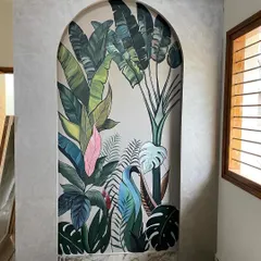 We love bringing the outdoors in. This tropical mural, framed by a beautiful archway, adds a burst of life and color to a hallway, making it feel like a lush paradise. The variety of leaves, including a pop of pink, creates a vibrant, layered look.