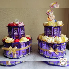 A pair of two-tiered chocolate "cakes" made from Cadbury Dairy Milk bars and decorated with artificial flowers. A sweet treat for any celebration.