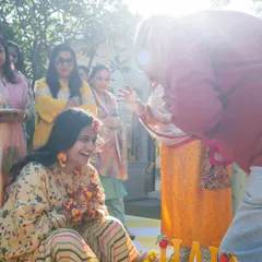 A candid shot of the bride laughing as her family applies haldi, a moment of pure joy and blessing.