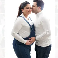 A sweet and gentle moment between expecting parents. This high-key studio shot with a clean white background emphasizes their connection.