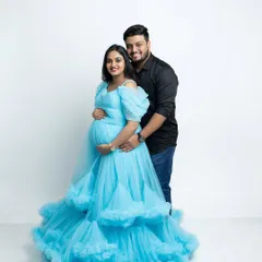 A lovely couple portrait from a maternity session. The expecting mother is in a beautiful blue gown, and her partner stands with her, creating a classic and happy memory before the baby arrives.