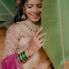 A playful and shy smile from the bride, Karishma. Her intricate henna, Maharashtrian nath, and the vibrant green bangles are the focus of this beautiful shot.