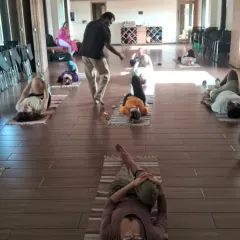 An instructor offers personalized correction on alignment during a group class. We prioritize safe and effective practice by ensuring each student understands the mechanics of the asana for their own body.