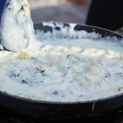 A close-up of creamy white sauce pasta being prepared at a live station. We use fresh ingredients like broccoli and high-quality pasta to create delicious Italian dishes on-site.