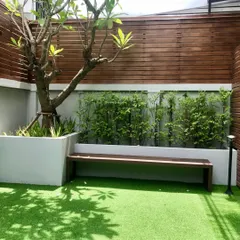 This cozy, shaded patio area combines a wooden bench and fence with a soft artificial grass floor. It’s a perfect example of creating a tranquil, low-maintenance garden retreat in a small space.