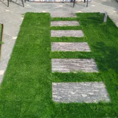 A close-up of the stone path and artificial grass combination. This design is practical and adds great visual texture to a terrace floor.