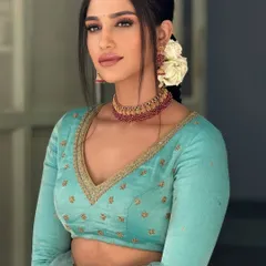 A model wearing a light blue, full-sleeved crop top with delicate embroidery. This versatile piece can be paired with a lehenga, saree, or pants for a modern ethnic look.