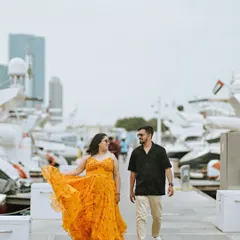 A candid walking shot of the couple at the Dubai marina, surrounded by luxury yachts. The focus is on their natural interaction and the grand scale of their surroundings.