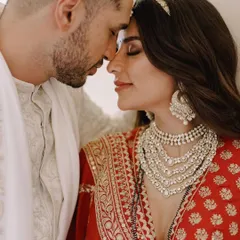 A duplicate of image 16, this intimate close-up of the couple highlights the bride's magnificent layered Tyaani Jewellery necklace and statement earrings, which were the centerpiece of her wedding look.
