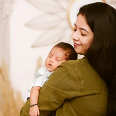 A mother's love captured in a quiet moment. She holds her sleeping newborn close, a simple and powerful portrait of the bond between mother and child.