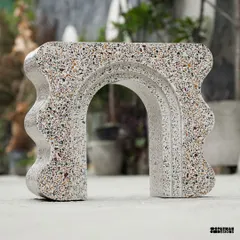 This view showcases the arched structure of the custom terrazzo bookshelf. The piece plays with positive and negative space, creating a sense of lightness despite being made from solid terrazzo.