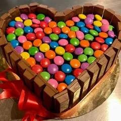 A chocolate lover's dream. This heart-shaped cake is bordered with KitKat bars and filled to the brim with colorful Gems.
