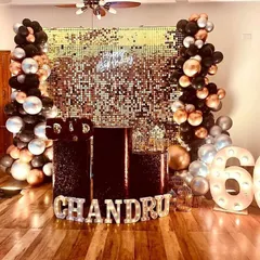 A glamorous 60th birthday party featuring a gold sequin shimmer wall, black and chrome balloons, and large marquee numbers.