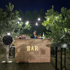 A rustic wooden bar set up under twinkling string lights for an outdoor Diwali party. It's the perfect spot for guests to grab a drink and mingle.
