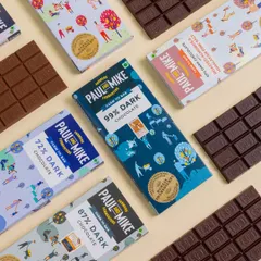 A flat lay of various Paul & Mike chocolate bars, showcasing the wide range of flavors and colorful packaging the brand offers.