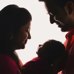 A beautiful silhouette of new parents admiring their baby. This artistic style creates a powerful and emotional portrait that focuses entirely on the new bond forming within the family.