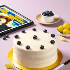 A blueberry lemon cake from The Big Chill Cafe, styled with fresh lemons and a movie poster prop to match the cafe's iconic theme.