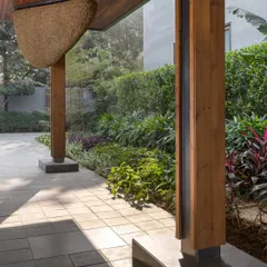 A detail of the entrance porch at the K Residence, showing the interplay of materials like wood, stone, and metal. A beehive sculpture by Vibha Galhotra hangs here, hinting at the art-filled interiors.