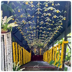 A unique ceiling treatment for the engagement ceremony pathway, using hanging ferns and marigolds to create a tunnel of foliage and flowers.