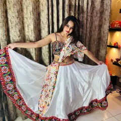 A beautiful white satin lehenga with a colorful embroidered border. The multi-color mirror work blouse and printed dupatta make it a standout piece for Garba.