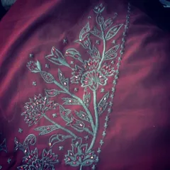 A detailed shot of floral embroidery on a rich maroon fabric. The combination of different stitches and subtle embellishments creates a beautiful, textured effect.