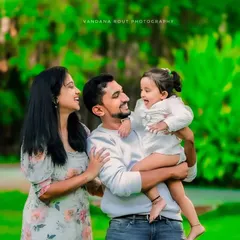 Laughter and joy fill this outdoor family portrait. The natural green background makes the family's bright smiles and interactions pop, creating a lively and happy memory.