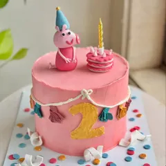 Too glam to oink. This custom Peppa Pig cake was made for a little one turning two, featuring a hand-molded fondant Peppa, a mini cake, and a colorful party theme.