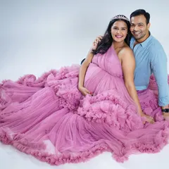 A sweet couple portrait featuring our pink tulle gown. The mom-to-be is seated comfortably, wearing a delicate tiara, creating a fairytale-like scene with her partner.
