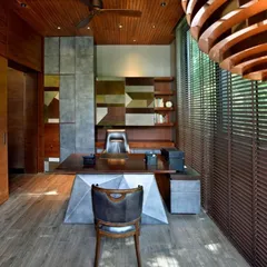 The interior of the cantilevered study, featuring a custom-designed desk and a rich palette of wood and metal. The space is crafted to be a sanctuary for focus and inspiration, sheltered by the canopy of a large tree.