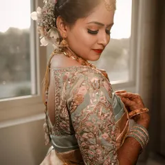 A sun-kissed portrait of a bride showing the detailed embroidery on the back of her blouse and the flowers in her hair. We capture the artistry of every element of the bridal look.